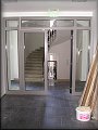 prosklené dveře ve vstupní chodbě v přízemí domu, vlevo a vpravo průchody do atria sboru, přímo schodiště domu 9.6.2009 